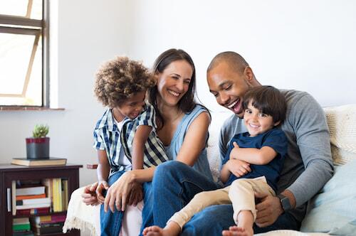 A family of four sitting on a couch together smiling
