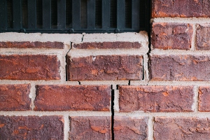 a wide foundation wall crack at the corner of a window