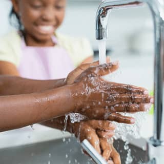 Hands being washed under a faucet