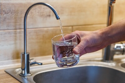 Homeowner filling a glass of drinking water from a sink