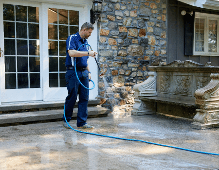 A worker pressure washing a concrete deck