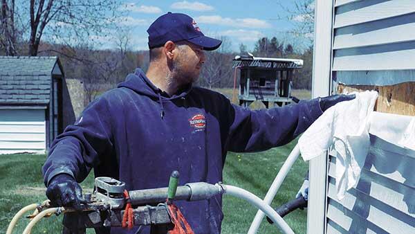 contractor injecting insulation through exterior of a home