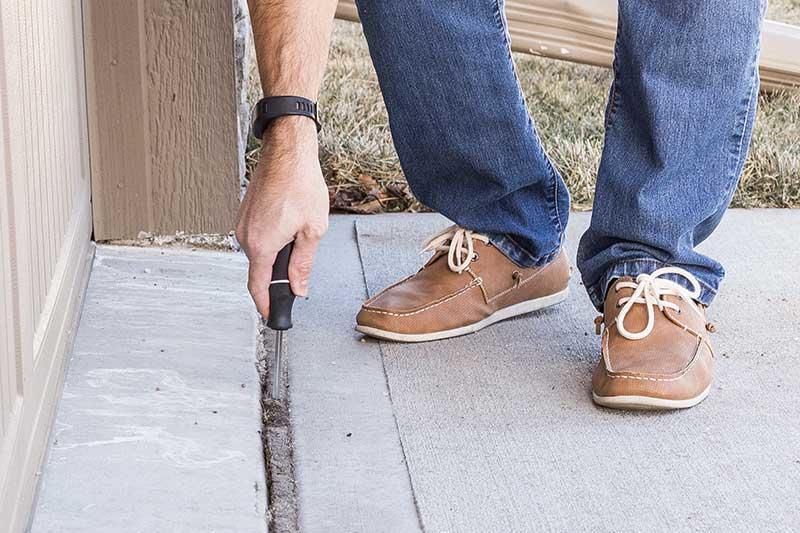 Man performing DIY concrete slab repair in driveway