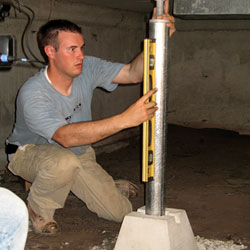 A crawl space contractor installing a support jack to add structural stability to the home