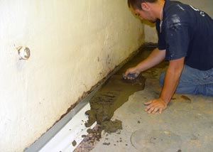 a contractor waterproofing a basement and performing a sump pump installation