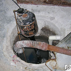 A pedestal sump pump system installed in a basement.