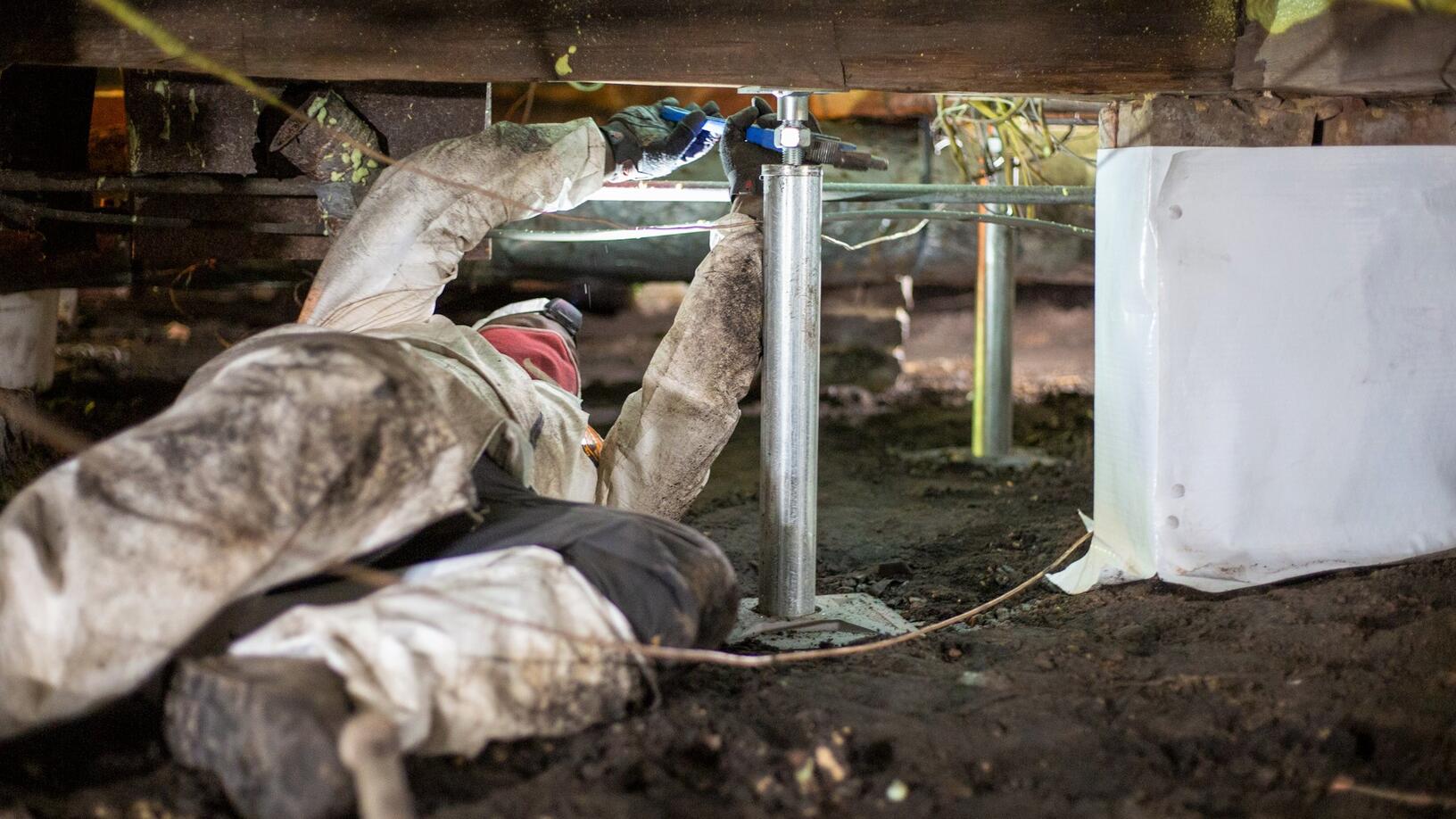 Foundation repair specialist working on crawl space drainage