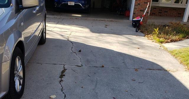 Sunken Cement Driveway Slabs Repaired in Port Washington, WI - Before Photo