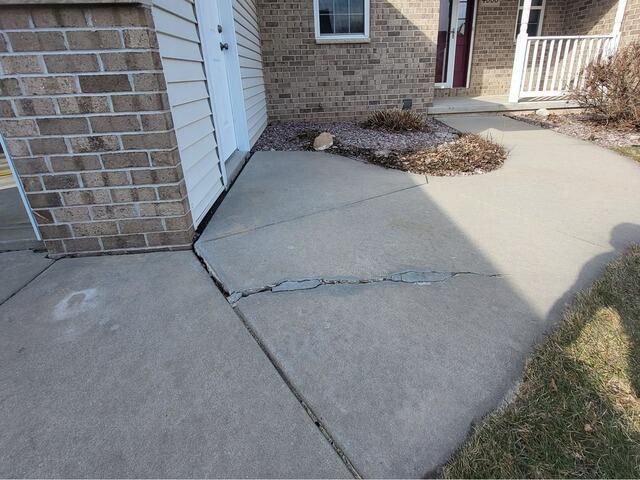 Uneven Driveway and Front Sidewalk Repaired in De Pere, WI - Before Photo