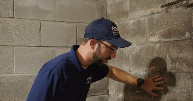 Checking the basement wall during an inspection.