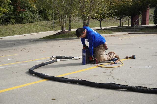 Frontier employee installing PolyLEVEL in a parking lot.