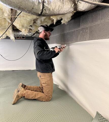 Frontier crew member installing CleanSpace on crawl space wall.