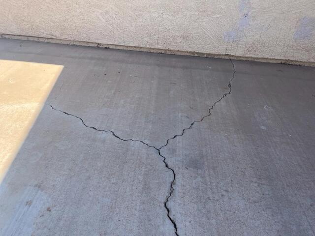 Concrete slab with visible foundation cracks near stucco wall in Arizona, needing foundation repair near me