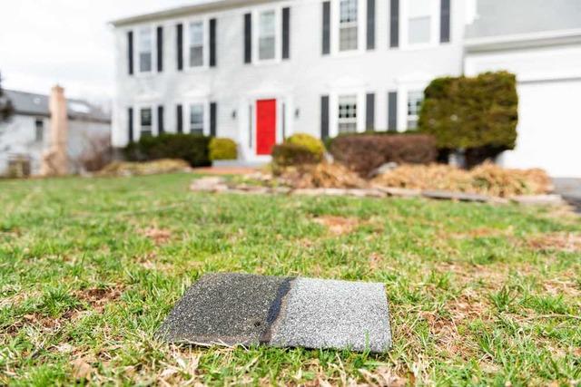 roof shingle on the ground in front of a house after a storm