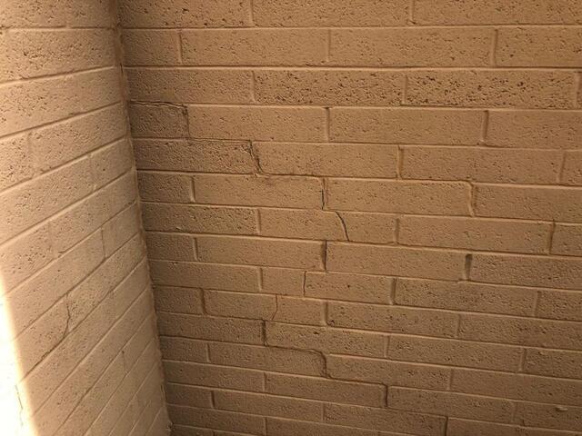 Stair-step cracks zigzag along the mortar joints of a block wall. This pattern usually points to settlement.