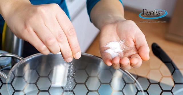 Person sprinkling salt into a pot of water