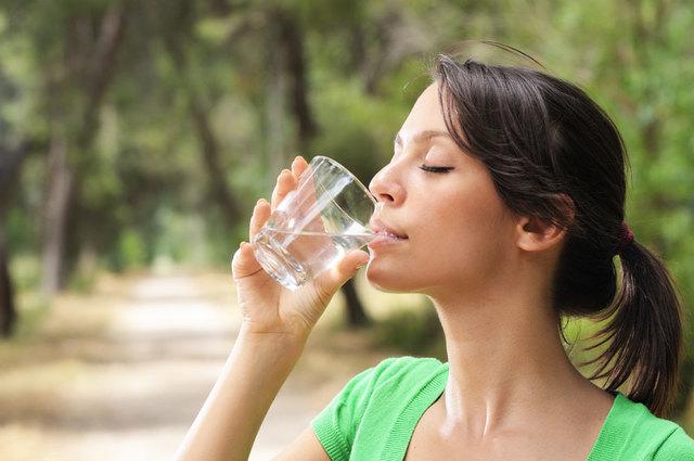 Woman drinking water from glass while outside