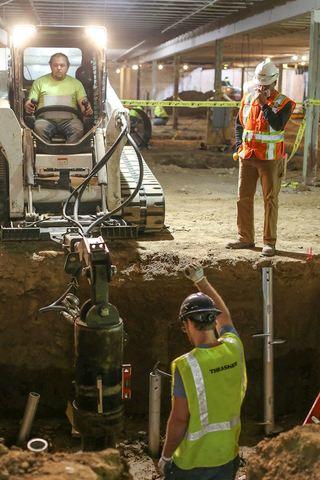 Heavy machinery driving helical pier into deep foundation