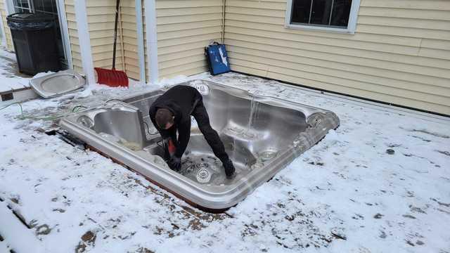 Sawing through the top of the hot tub to allow easier removal.