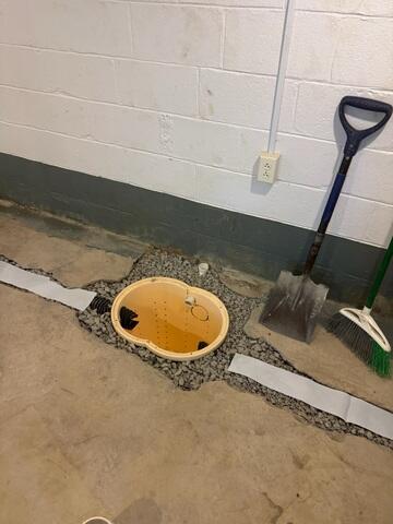 This photo shows the first step in the process, where we trenched the slab a couple feet away from the wall. The drains, sump basin, and interval ties have all been graded with gravel, and are ready to be sealed.