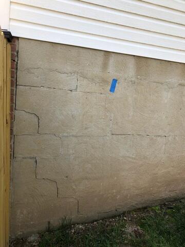 Stair-step cracks on the exterior walls indicate significant foundation problems requiring immediate attention.