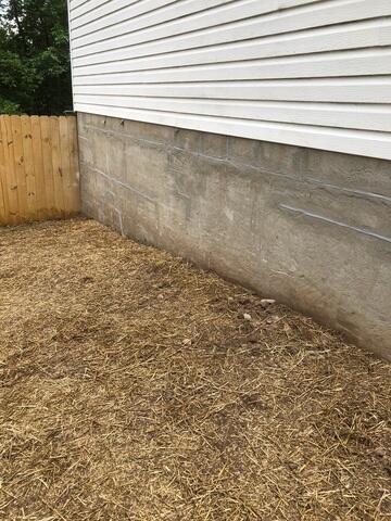 Helical piers were installed, the wall sealed, and the area refilled with dirt and grass seed, preparing the site for the installation of wall anchors.