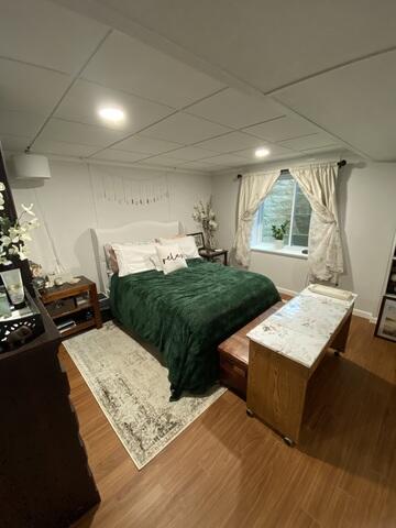 The basement was completely transformed into a bright, comfortable living space with finished walls, Elite Plank flooring in dark walnut, and soft overhead lighting. A new egress window brings in natural light, while clean design details and cozy furnishings give the daughter her own private, modern retreat-proof that this space is now so much more than just a basement.