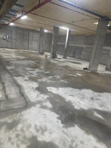 Water routinely collected across the garage floor, posing safety risks and signaling poor drainage and an uneven slab.