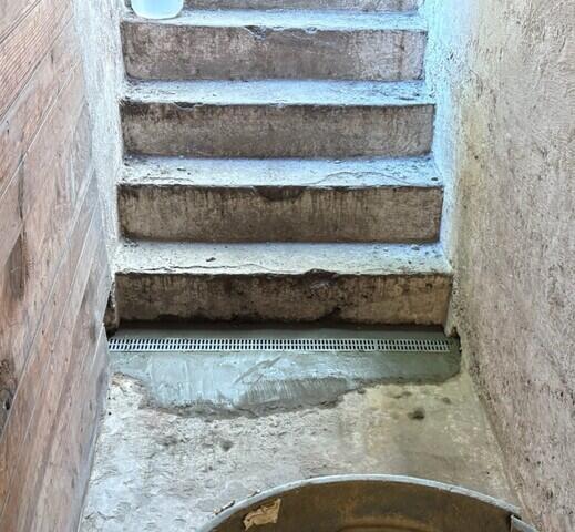 The TrenchDrain grated basement drain is installed at the base of the bulkhead stairs to collect surface and excess water.