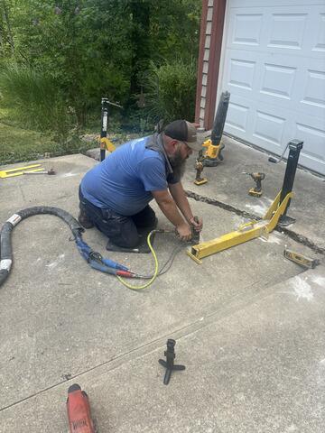 This photo shows our Tech, David, injecting the foam underneath the slab. The tool connecting both of the slabs together is called our SlabJacker tool, which helps us manually steer the slabs back together as we're injecting the foam.