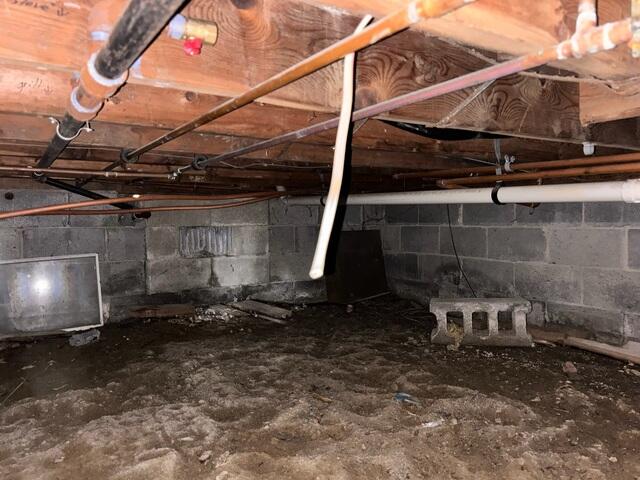 The crawl space was unprotected, with bare walls and no insulation, allowing moisture and outside air to seep in.