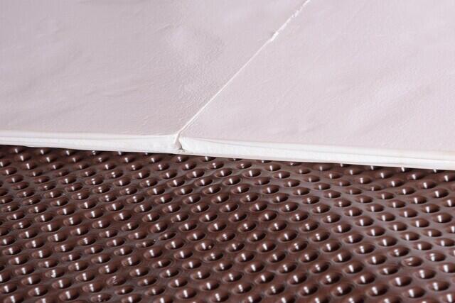This photo shows what we installed overtop the gravel floor of the  crawl space. We started by nailing our brown dimpled drainage matting over the gravel. We then laid down our white TerraBlock floor insulation over the drainage matting.These two products are then concealed with our CleanSpace vapor barrier, (not yet pictured).