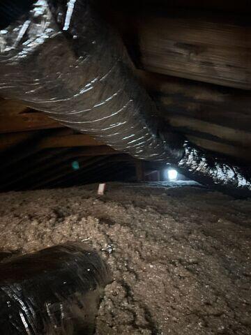 After all that work is done down at ceiling level, the cellulose insulation is blown-in. The top of one of the red/white rulers is just visible left of center.
