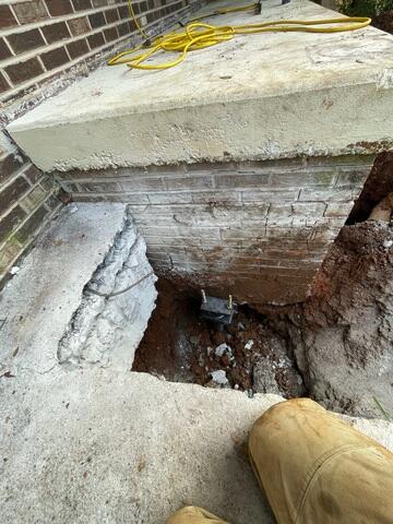 Helical pier bracket installed under the porch to provide deep foundational support.