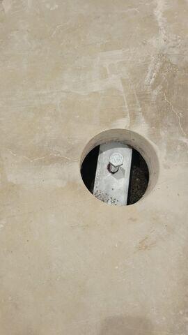 This photo provides a close-up look at one of the pier brackets used in the project. The bracket is attached directly beneath the slab and serves as the point where the hydraulic system lifts the concrete back to its proper level. Once the slab is raised, the bracket holds it securely in place, transferring the weight of the floor down to the stable soil or bedrock below.