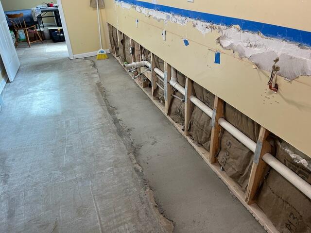 This photo shows what our inspector found during the initial visit. You can see how far the previous contractor had to cut back the concrete from the wall to install their drainage system.