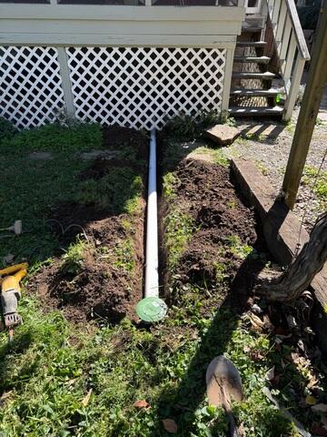 Discharge line exposed during installation, showing the pop-up outlet before final backfilling.