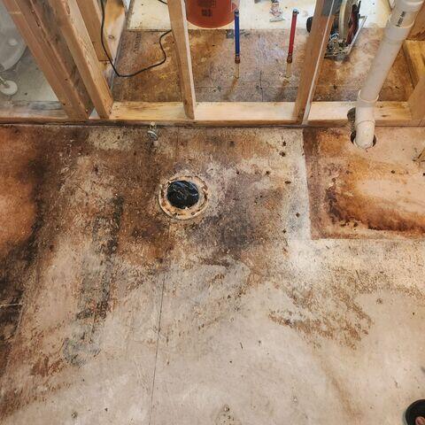 Before rebuilding the bathroom after a leak, mitigation and remediation must be completed. Drying fans and dehumidifiers continue to lower humidity levels, and unsalvageable materials are removed, exposing the subfloor.