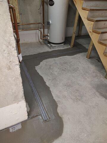 WaterGuard® Interior Drainage System: Installed along the interior perimeter of the basement floor, WaterGuard captures groundwater seepage from the walls and floor joint, directing it safely to the sump pump. Its clog-resistant design ensures long-term reliability.

TrenchDrain™ System: To address surface water entering through the bulkhead area, a TrenchDrain was installed and connected directly to the WaterGuard system. This ensures that any water entering near doorways or entry points is immediately collected and diverted.