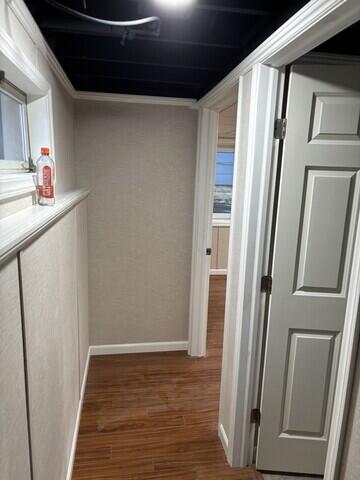 This hallway showcases the seamless transition between rooms, featuring durable wood-look flooring and crisp white trim. The open ceiling painted black adds contrast and a contemporary touch.