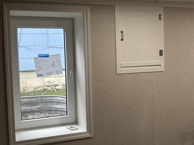 A newly installed egress window brings in plenty of natural light, brightening the finished basement. The clean trim and neutral wall panels create a polished, modern look.