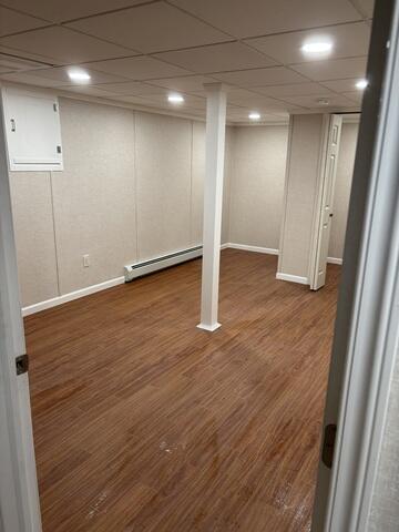 The main living area of the remodeled basement - spacious, bright, and ready to use. Fresh wall panels, a drop ceiling with recessed lighting, and wood-look floors give the room a warm, inviting atmosphere.