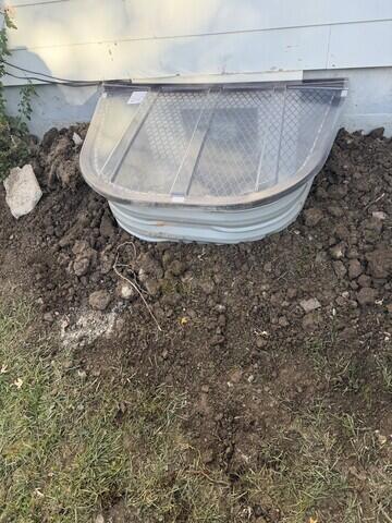 This image shows the finished egress window with the cover installed. The clear, durable cover keeps out rain, leaves, and debris while still allowing sunlight to pass through. It gives the project a neat, finished appearance from the outside and ensures long-lasting protection for the window well below.