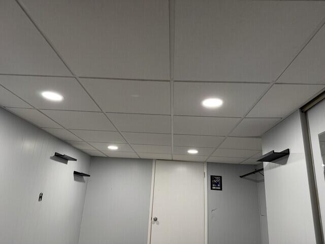 The new drop ceiling features fresh, uniform tiles that completely transform the space. The clean white finish brightens the room, giving it a polished and updated look while maintaining easy access to the ceiling above. A simple upgrade that makes a big difference!