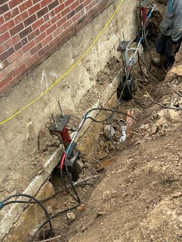 This photo provides a closer look at the pier brackets secured beneath the footing. At this stage of the project, our hydraulic attachments were connected, allowing us to carefully lift and relevel the structure.