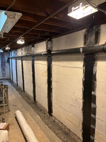 CarbonArmor straps installed along the block foundation wall, with a trench opened at the footer in preparation for the WaterGuard drainage system.