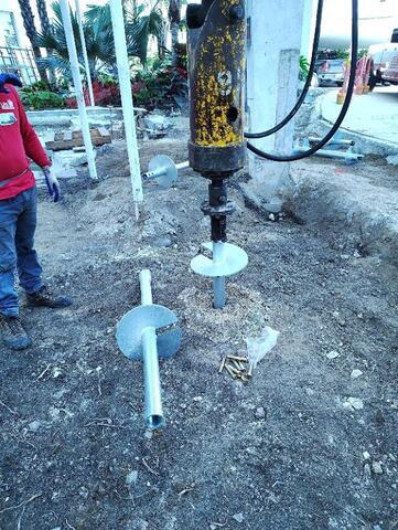 Installing helical pile 10"-12"-14" lead section with 14" extension in foreground.