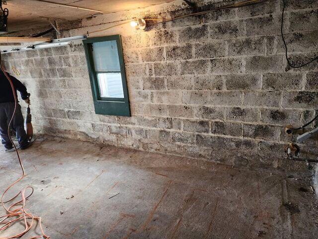 The basement before the install, showing dampness and moisture along the walls and floor.