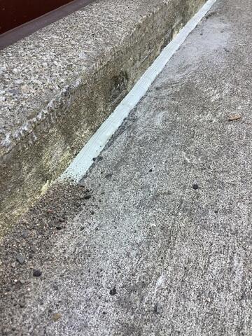 Following the application of the flexible sealant, we apply polymeric sand into the surrounding joints. This specialized sand hardens when cured, serving a critical structural function: it helps to lock the concrete slabs in place, effectively preventing further movement or sinking away from the house wall. This step is key to achieving long-term stabilization.