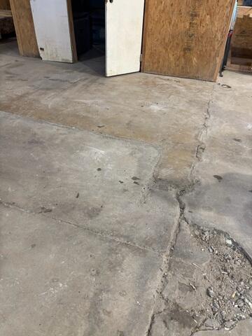 High-traffic areas near entryways often face the most stress. This severe fracturing and sinking indicate deep-seated voids that require professional stabilization to prevent further slab failure and ensure a safe, reliable workspace.
